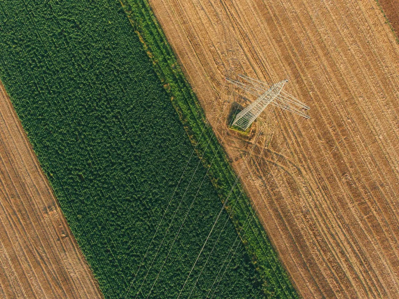 Aerial view of transmission tower between crop fields